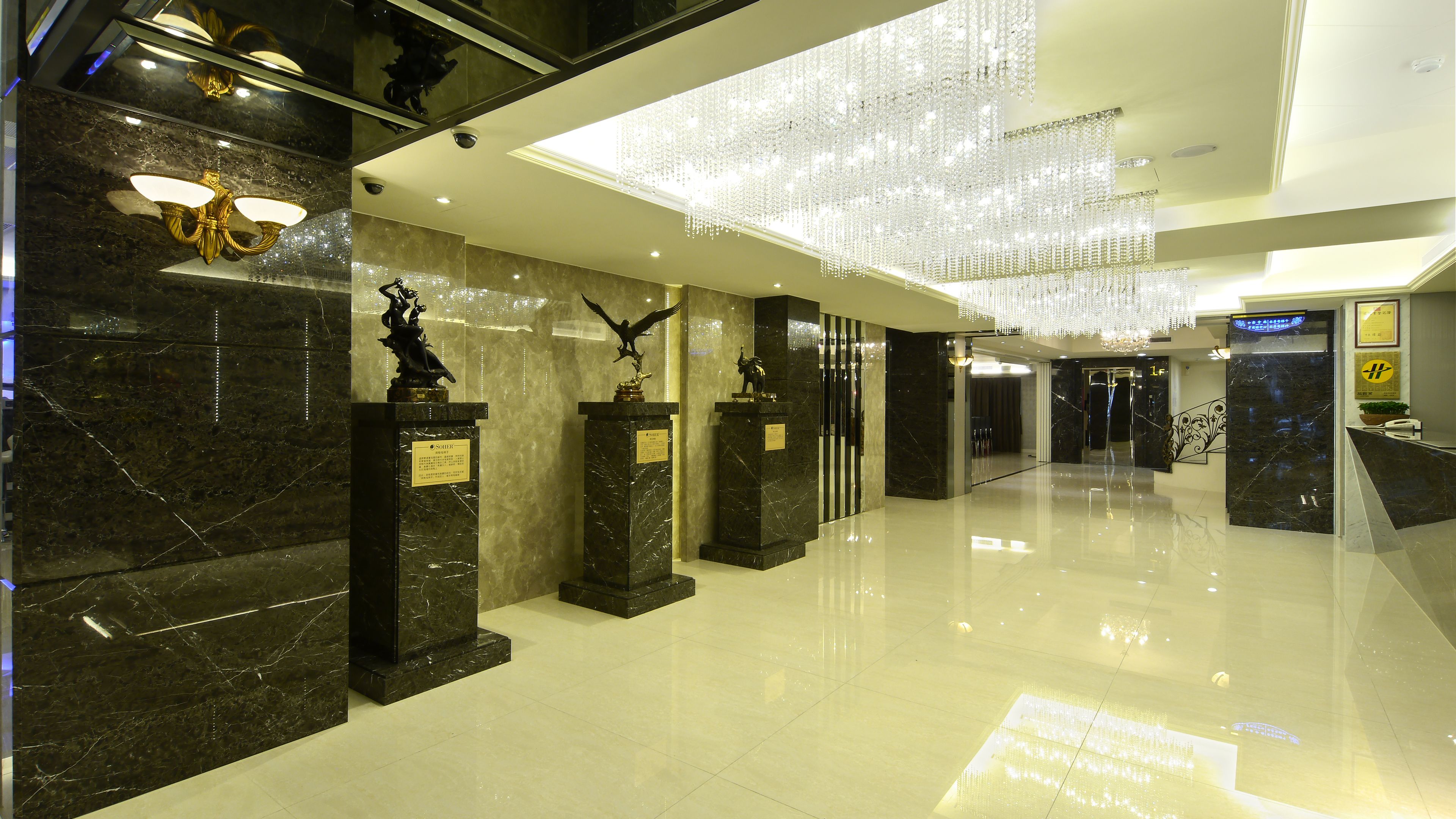 Eine Lobby mit Marmorwänden, einem Kronleuchter und Statuen auf Sockeln.