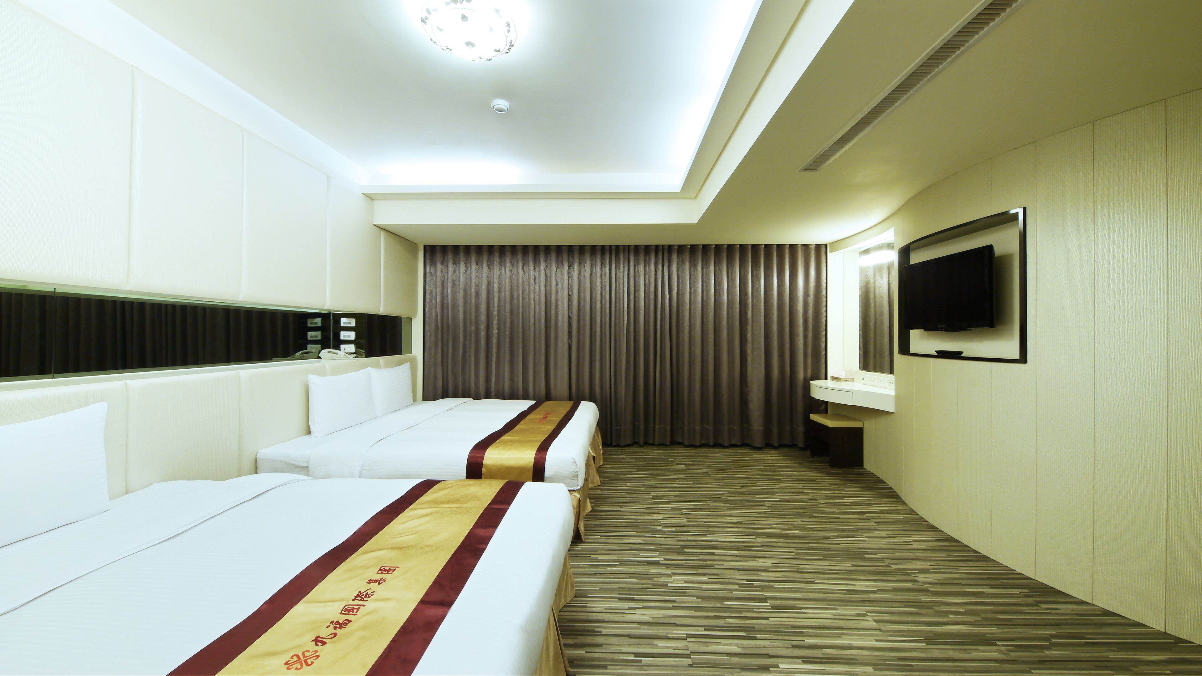 Una habitación de hotel con dos camas, televisión, espejo y baño.