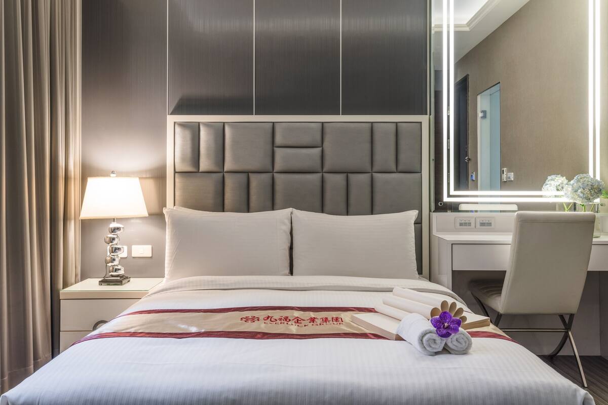 Une chambre d’hôtel comprenant un lit, une table de chevet avec une lampe, un bureau avec une chaise et un grand miroir.