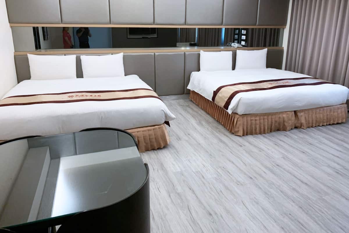 Une chambre d’hôtel avec deux lits, une petite table et un miroir.