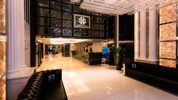 A hotel lobby with a reception desk, seating area, and a chandelier.