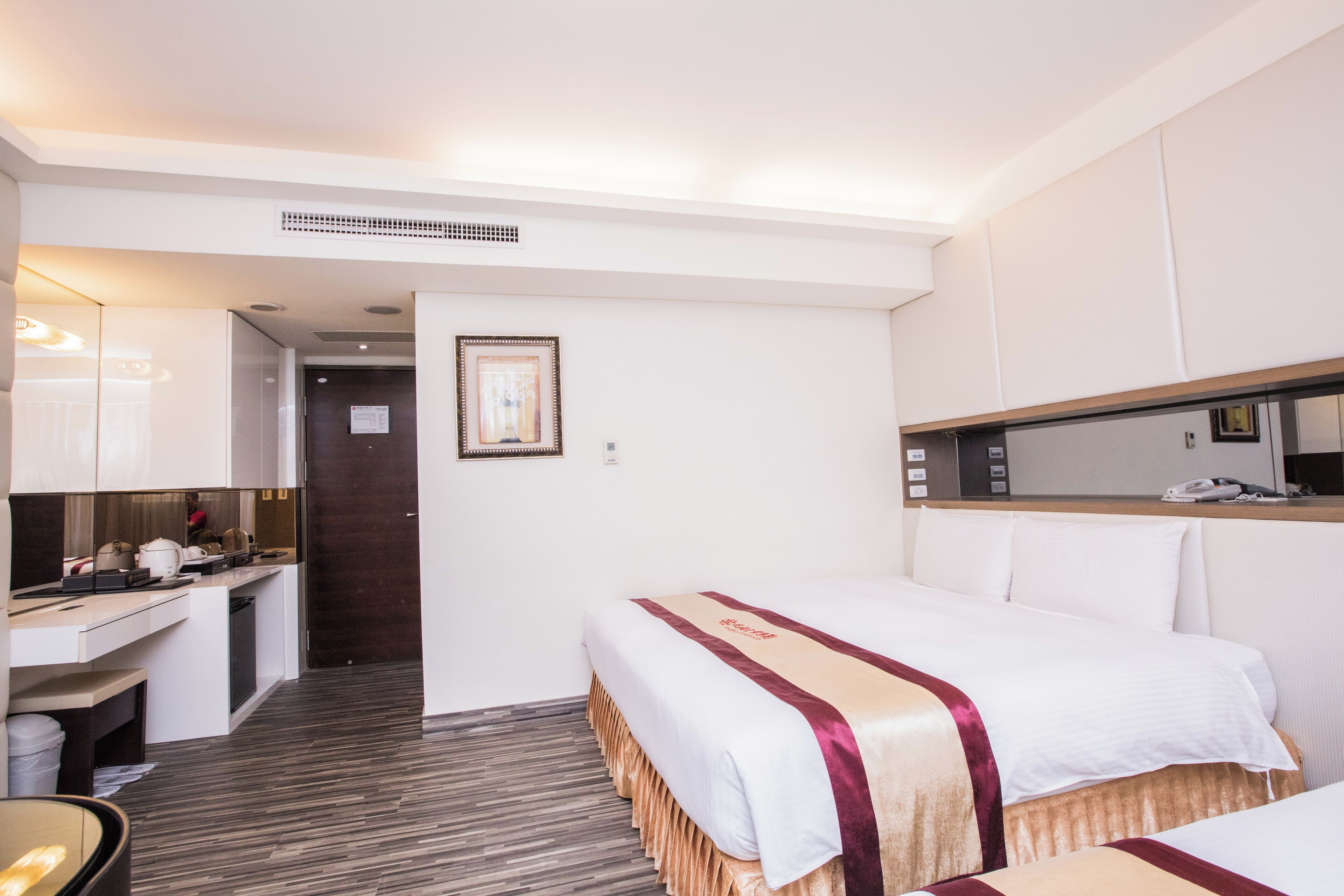 A hotel room with a bed, a desk, and a small kitchenette.