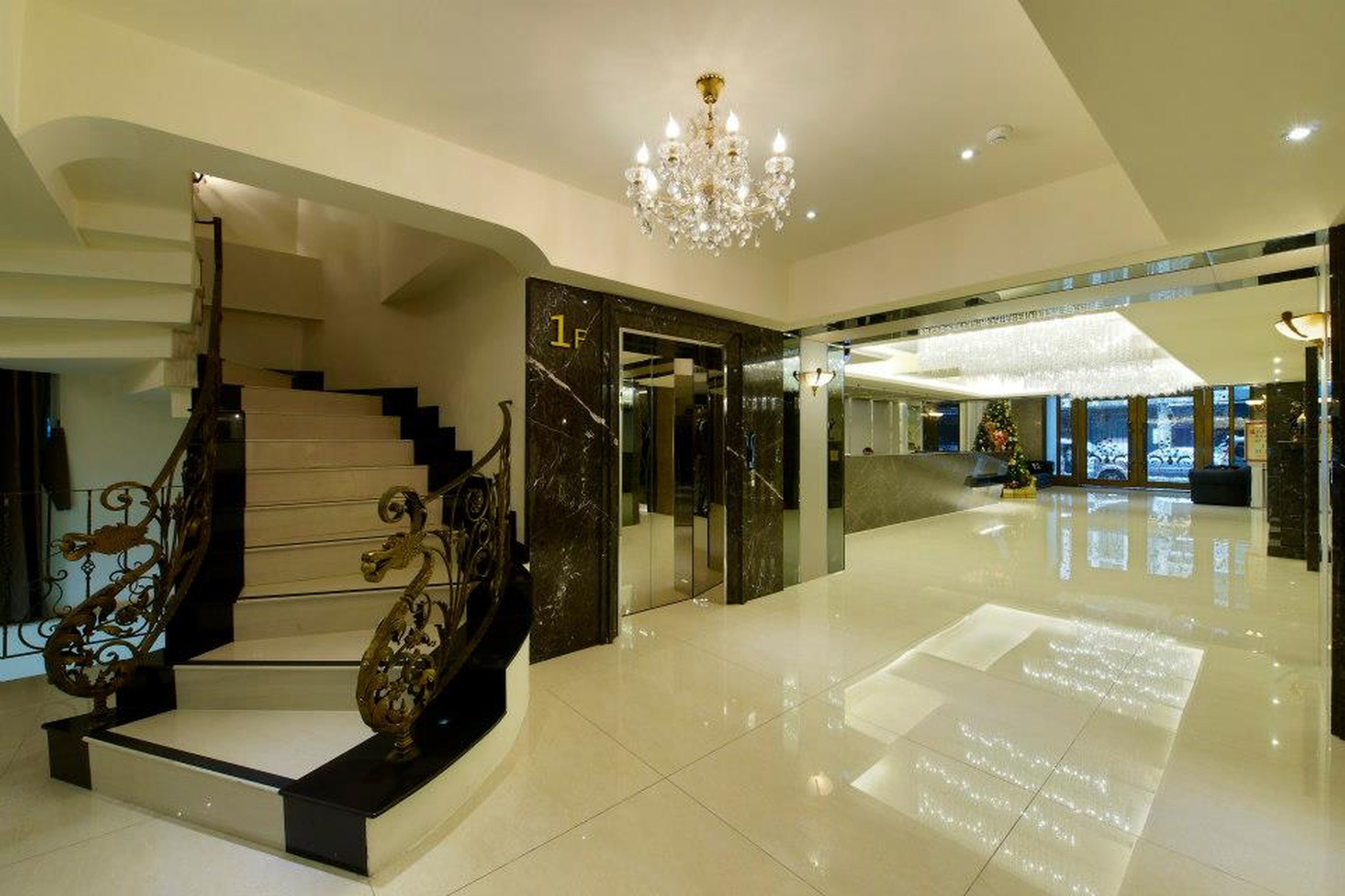 Un hall espacioso con una imponente escalera, un candelabro y un árbol de Navidad.