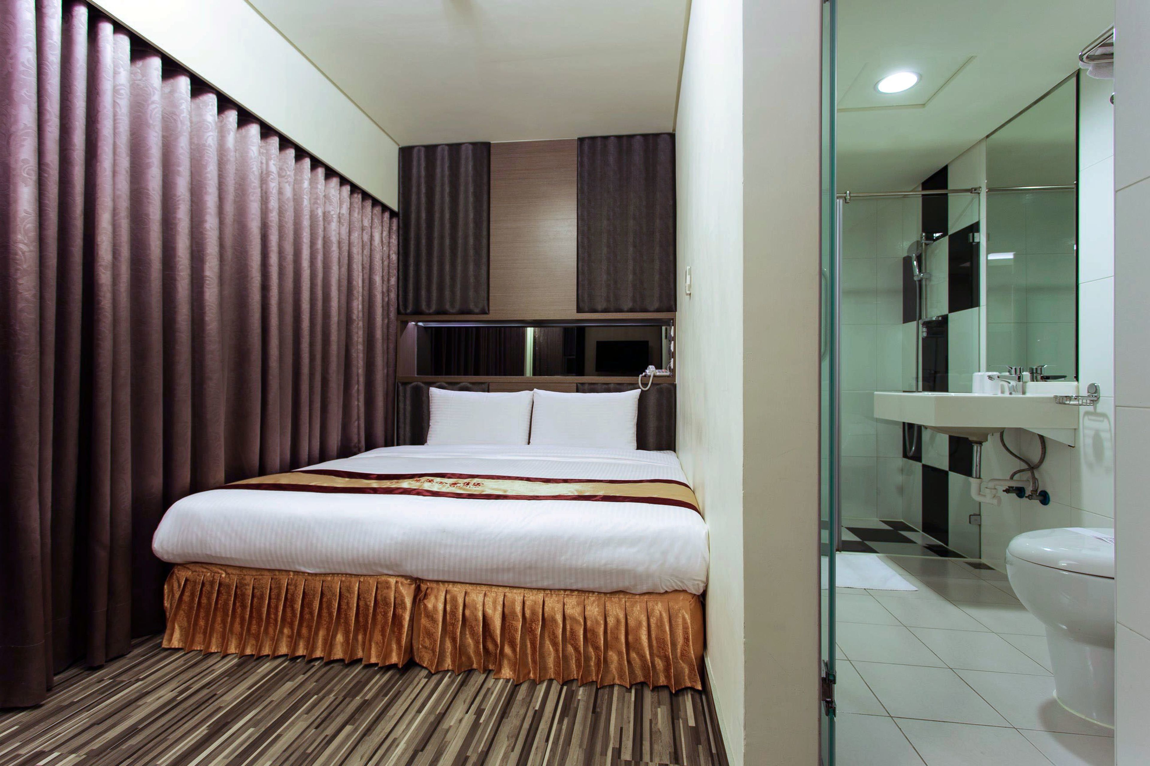 A hotel room with a bed, a bathroom with a glass shower enclosure, and a sink.