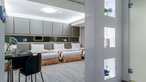 A hotel room with a bed, a desk with a chair, and a small table with a vase of flowers. - Harmonious Hotel (Kaohsiung)