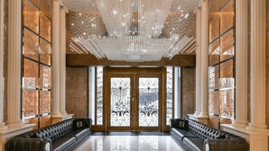 A grand lobby with a reflective floor, ornate chandeliers, and two black leather sofas with decorative pillows. - Harmonious Hotel (Kaohsiung)