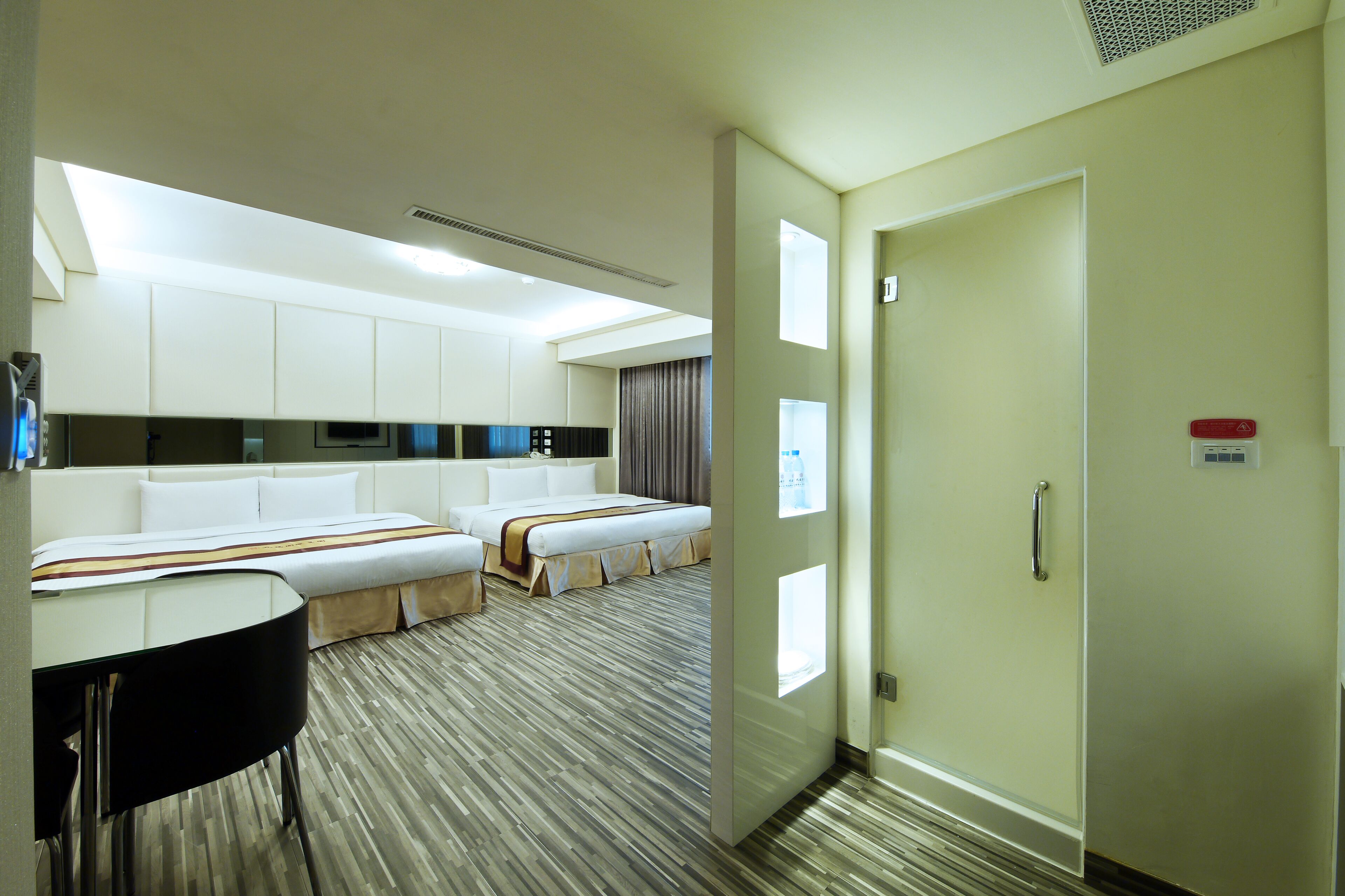 A hotel room with two beds, a desk, and a bathroom.