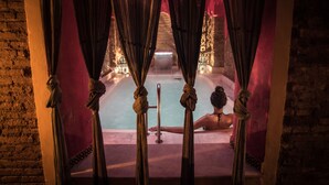 Uma área de spa com hidromassagem, cortinas e uma parede de tijolos.