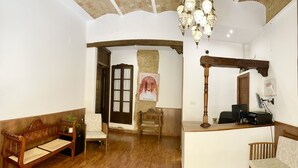 Uma área de recepção com um banco de madeira, uma mesa com computador e um lustre.