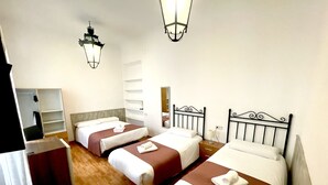 Quarto de hotel com duas camas, um guarda-roupa e um espelho.