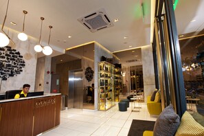 A hotel reception area with a wooden reception desk, a wall of cameras, and a glass display case with items.