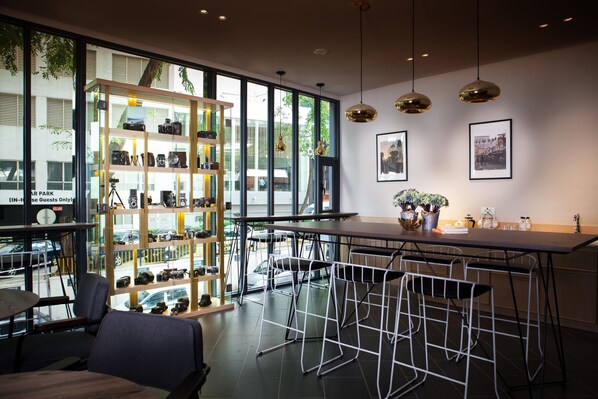 A modern interior with a glass wall, metal bar stools, and a display of cameras.