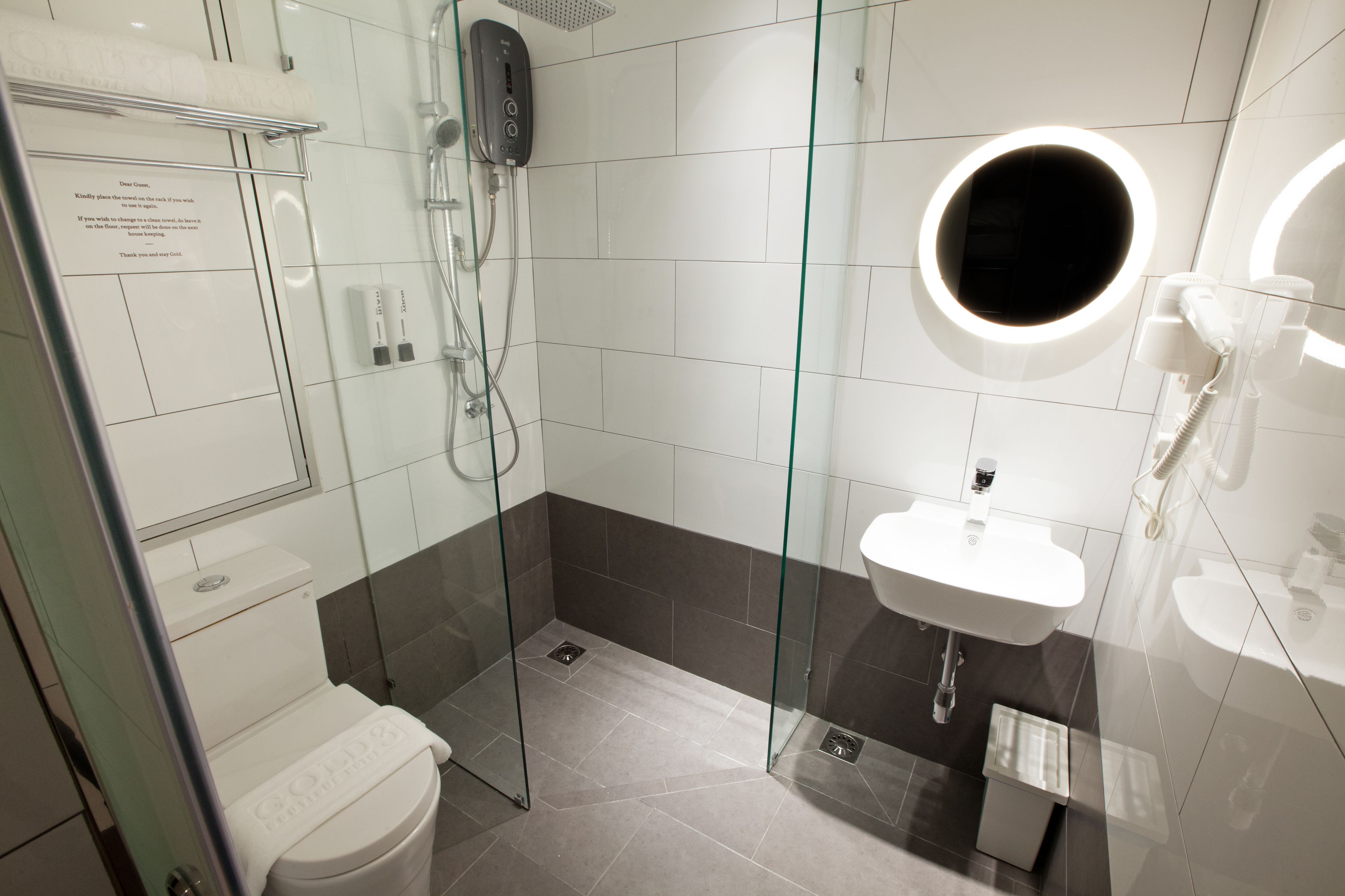 Un baño moderno con ducha de vidrio, un lavamanos blanco y un inodoro.