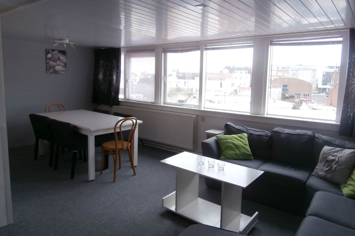 Een moderne woonkamer met een eethoek, grote ramen en uitzicht op de stad.