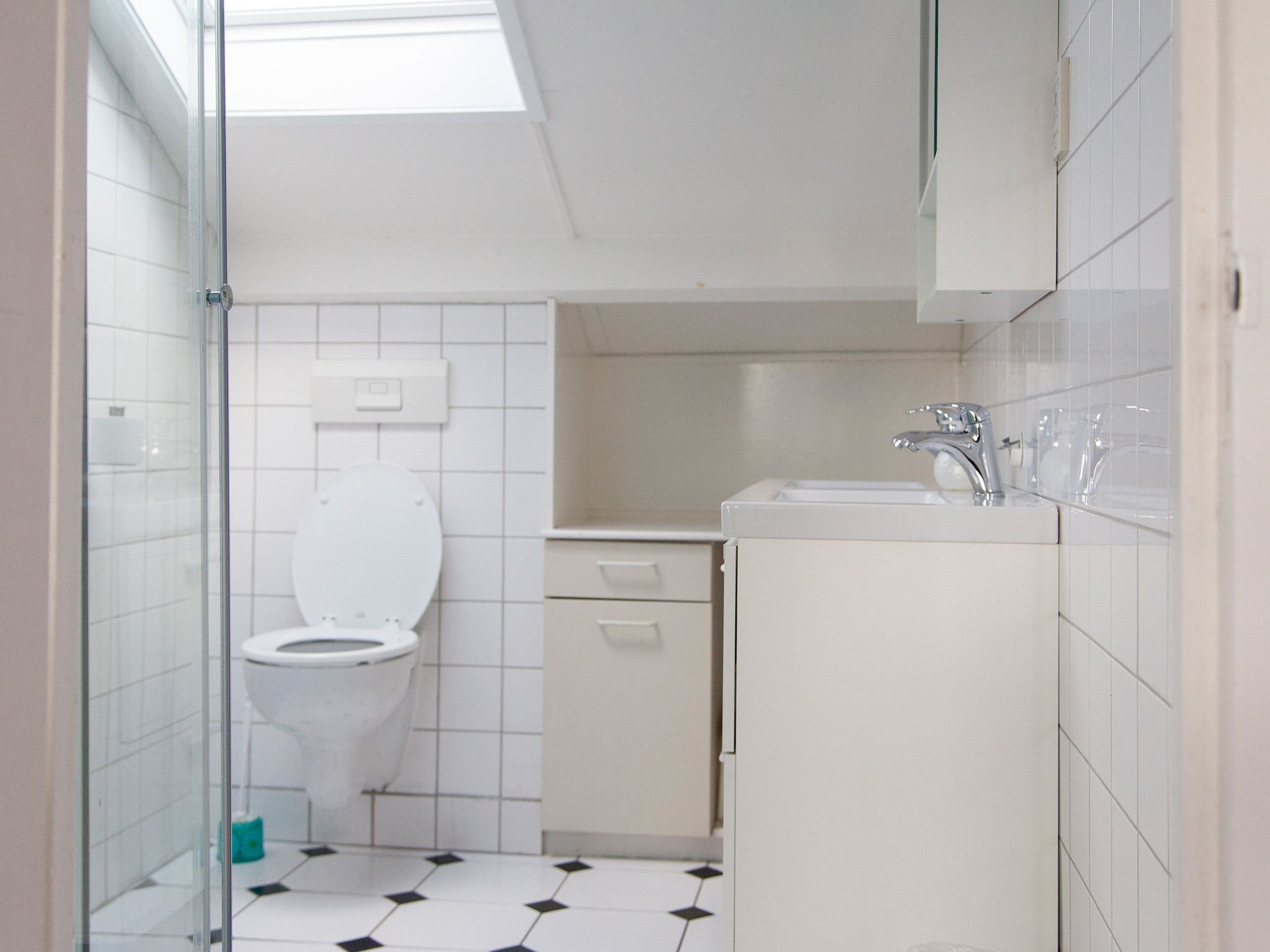 Un baño con inodoro, lavamanos y cabina de ducha de vidrio.