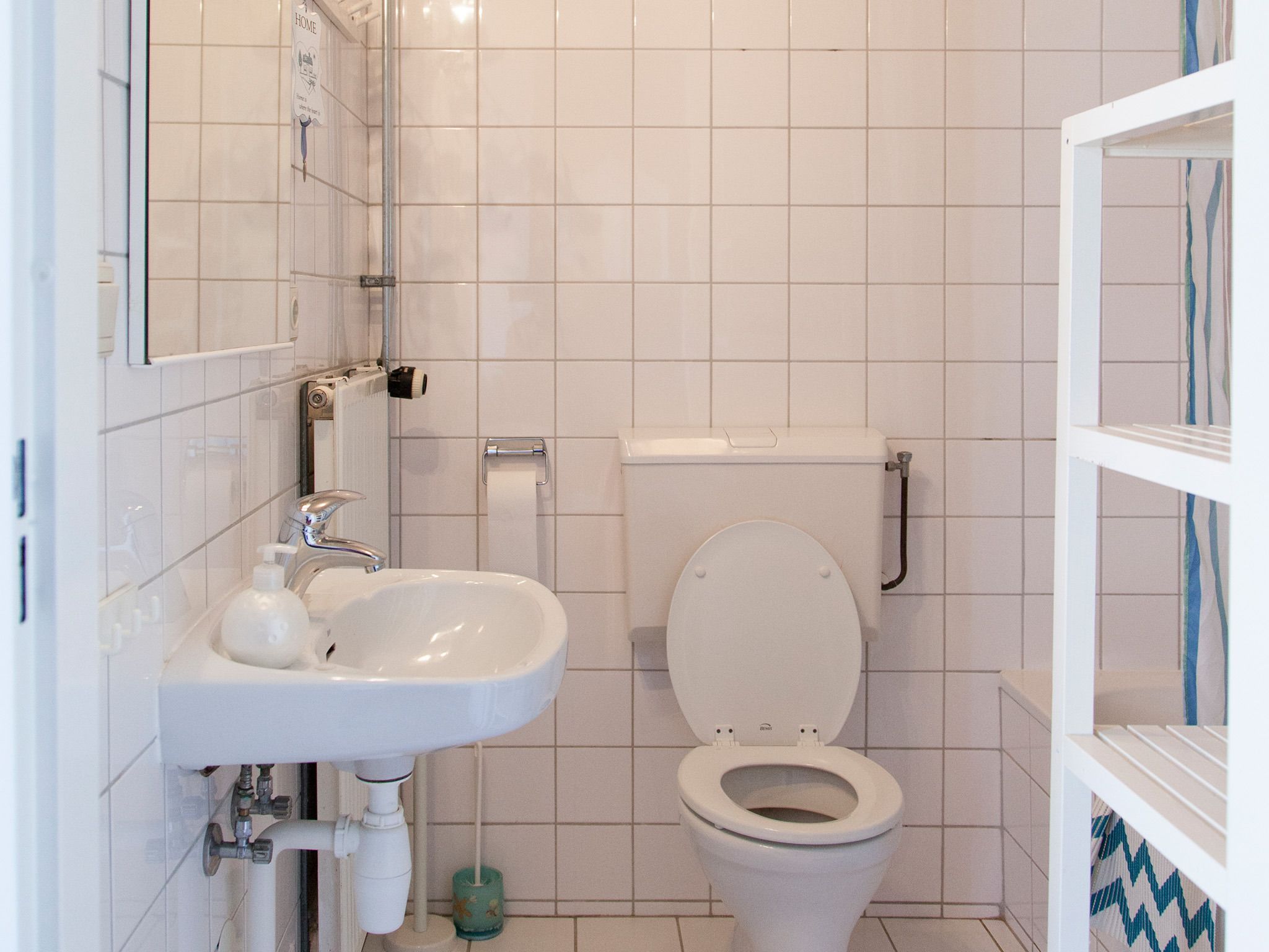 Une salle de bain avec un lavabo, des toilettes et une douche, le tout de couleur blanche.