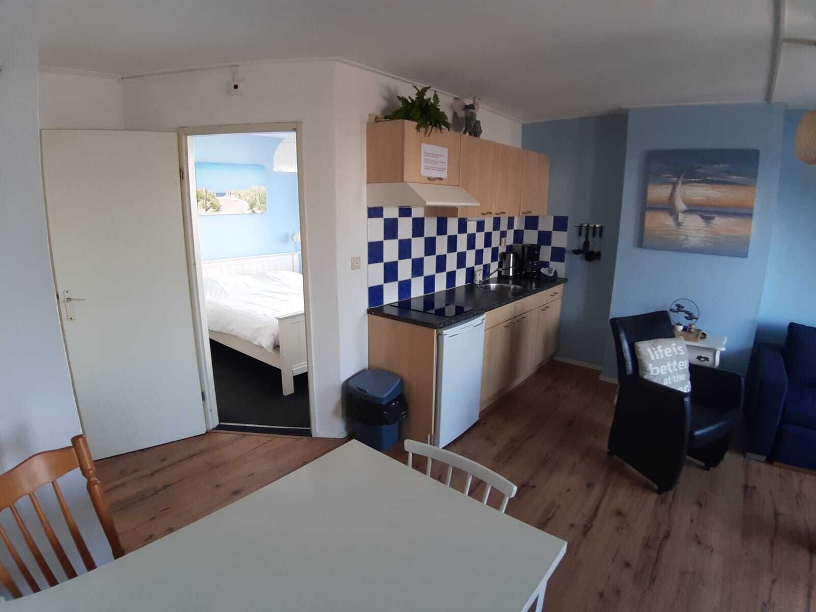 A compact room with a bed, a kitchenette, a dining area, and a view of the outdoors.