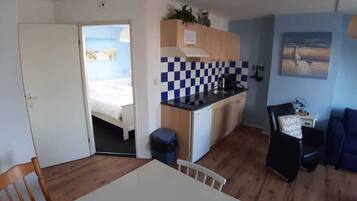 A compact room with a bed, a kitchenette, a dining area, and a view of the outdoors.
