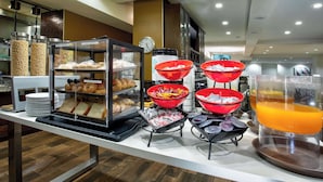 A breakfast buffet with various food items and a clock on the wall.
