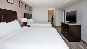 A hotel room with two beds, a TV, and a dresser.