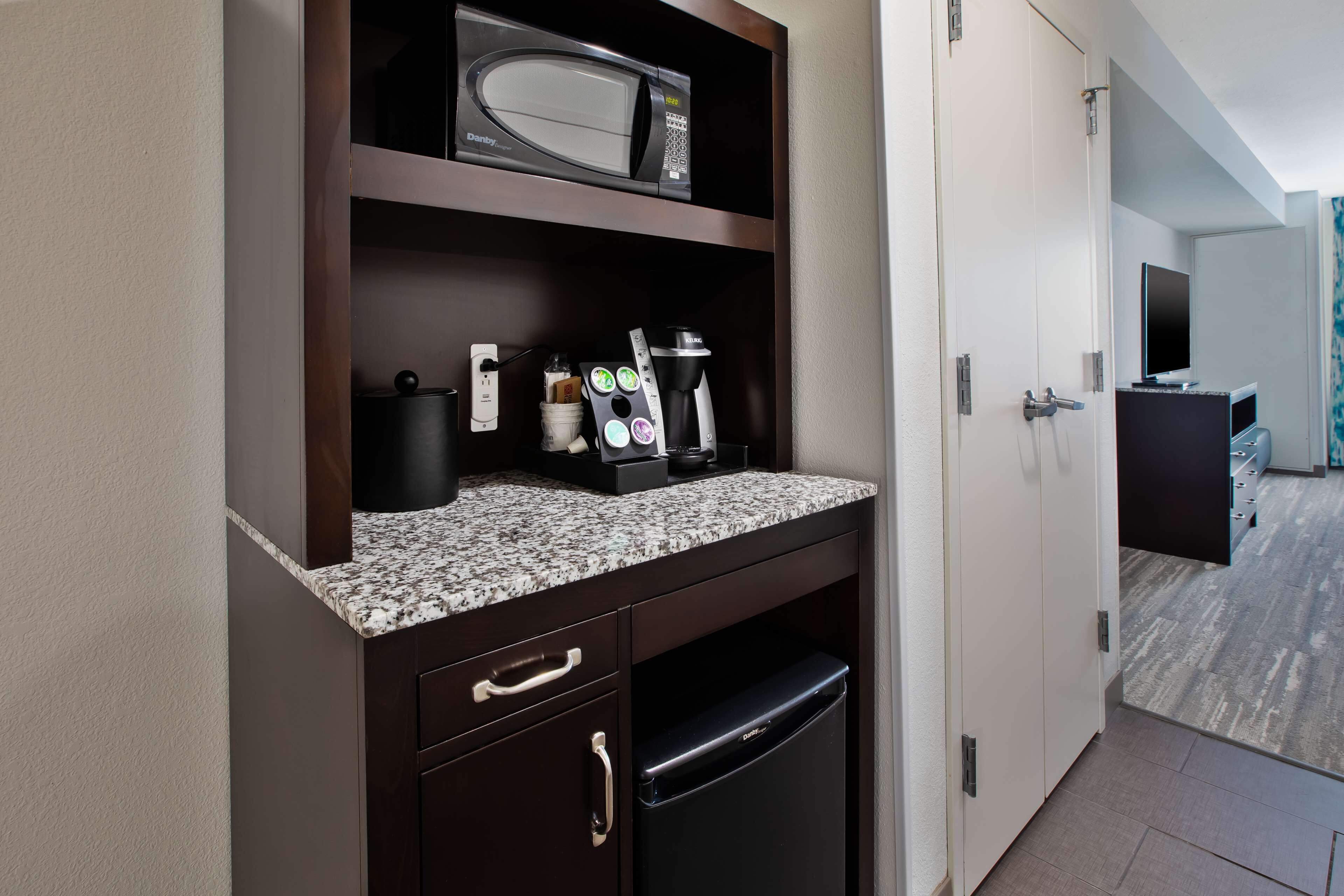 A compact kitchenette with a microwave, coffee maker, and a small refrigerator.