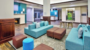 A spacious lobby with a large seating area, a fireplace, and a view of the outdoors.