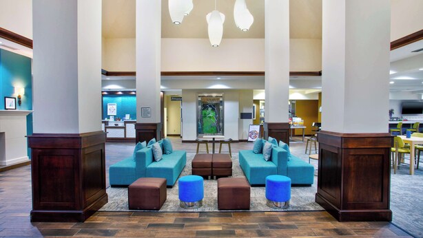 A spacious lobby with a central seating area, large pillars, and hanging pendant lights.