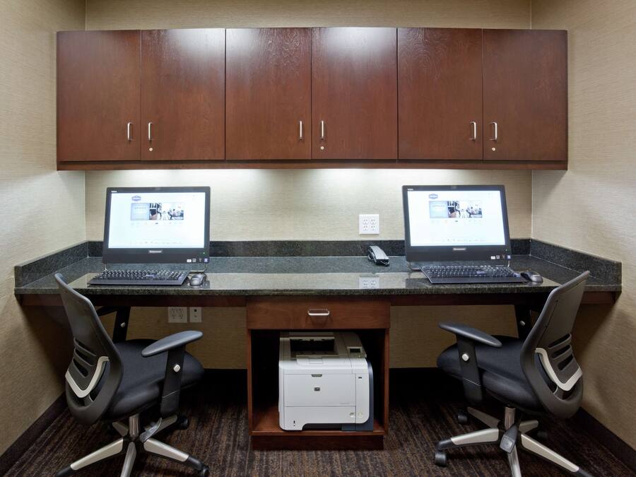 A workspace with two desks, each with a laptop, two office chairs, and a printer.