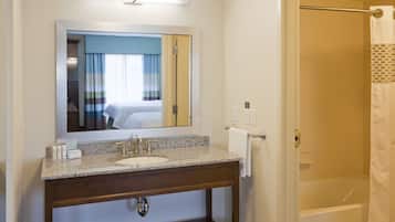 A bathroom with a sink, mirror, and shower.