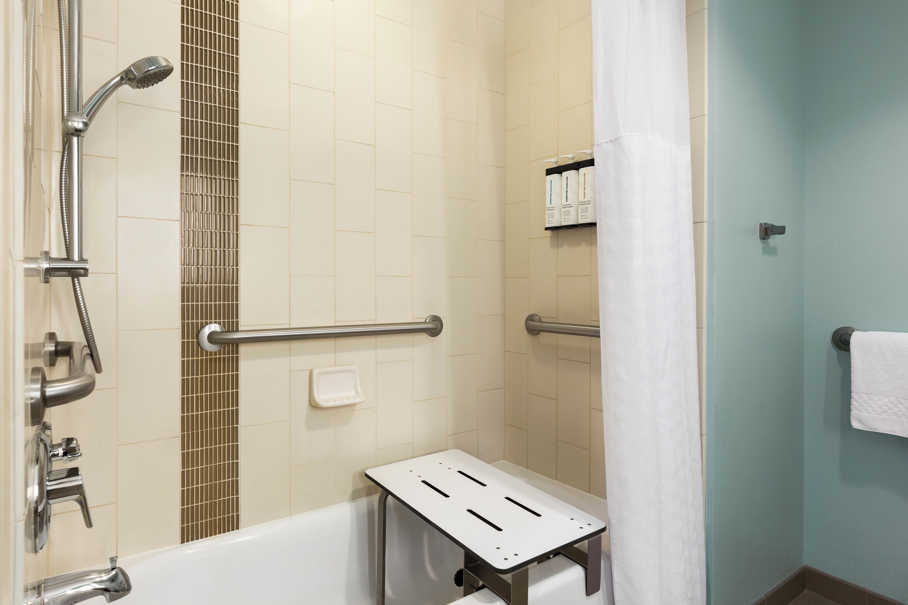 Ein Badezimmer mit Dusche, Haltegriffen, Handtuchhalter und Seifenschale.