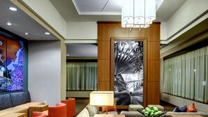 Eine moderne Hotelhalle mit Sitzgelegenheit, einem Holzbüro und einem großen Wandbild.