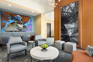 Un hall d’entrée doté de mobilier moderne, une table ronde agrémentée d’un centre de table composé de fruits et de grandes œuvres d’art abstrait ornant les murs.
