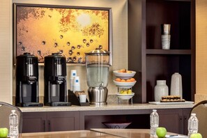 Un bar pour le petit-déjeuner équipé de machines à café, d’un panier de fruits et d’un distributeur d’eau.