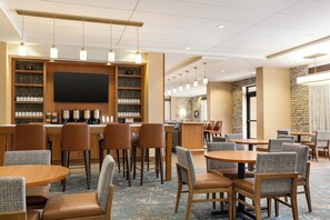 Un hall de hotel con área de bar, asientos y una pantalla grande.
