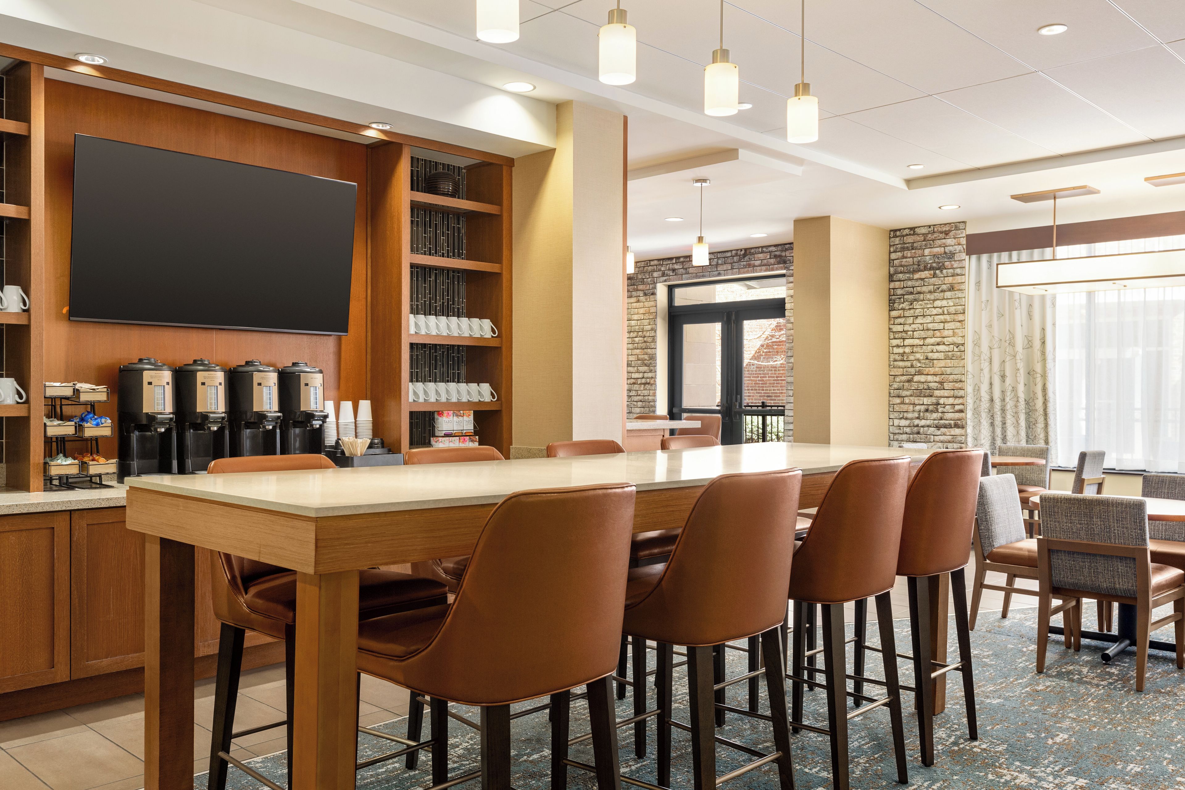 A conference room with a long table, chairs, a coffee station, and a large screen.