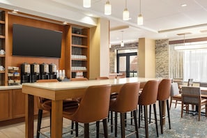 Une salle de conférence équipée d’une longue table, de chaises, d’un coin café et d’un grand écran.
