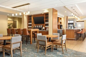 Een hotel lobby met een bar, zitgedeelte en een groot scherm.
