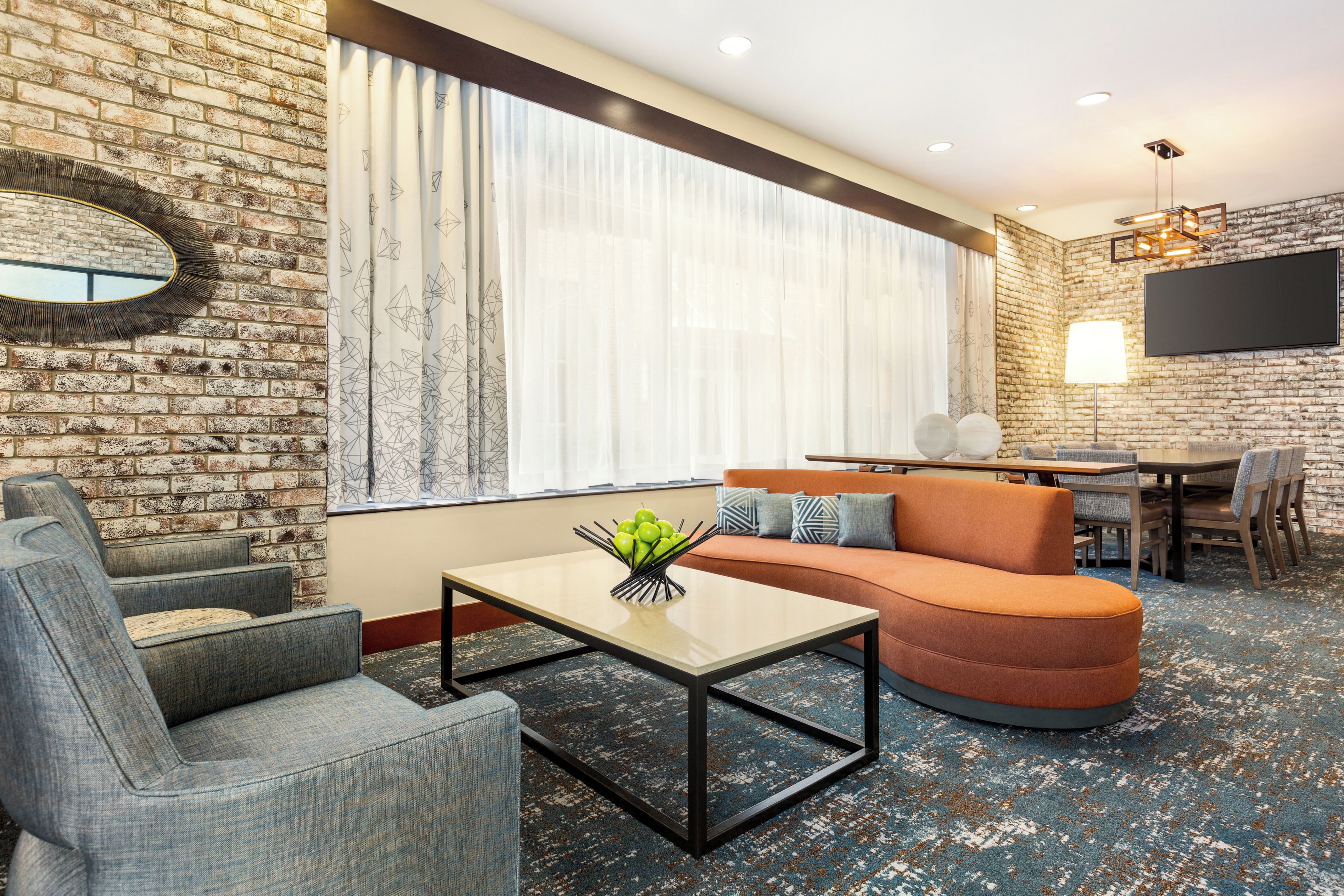 A modern living room with a brick wall, a sofa, a coffee table, and a TV.