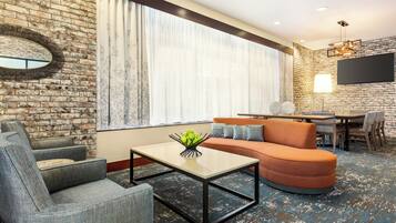 Una sala de estar moderna con pared de ladrillo, un sofá, una mesa de centro y un televisor.