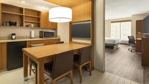 Une cuisine moderne avec des meubles en bois, une table à manger avec des chaises, un four à micro-ondes et un tableau noir accroché au mur.