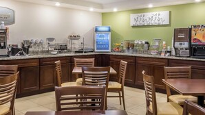 Un área de cocina moderna con estación de café, asientos y un refrigerador.