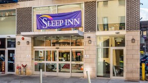 Un hotel Sleep Inn con un llamativo cartel morado, puertas de cristal y un indicador cajero automático.
