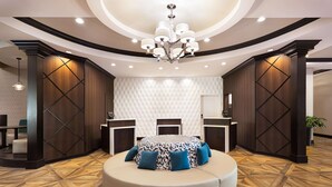 Un moderno vestíbulo de hotel con un área de asientos circular, una araña y un piso con diseño.