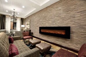 A modern living room with a fireplace, comfortable seating, and a chandelier. - DoubleTree by Hilton Charleston Mount Pleasant (Mount Pleasant)
