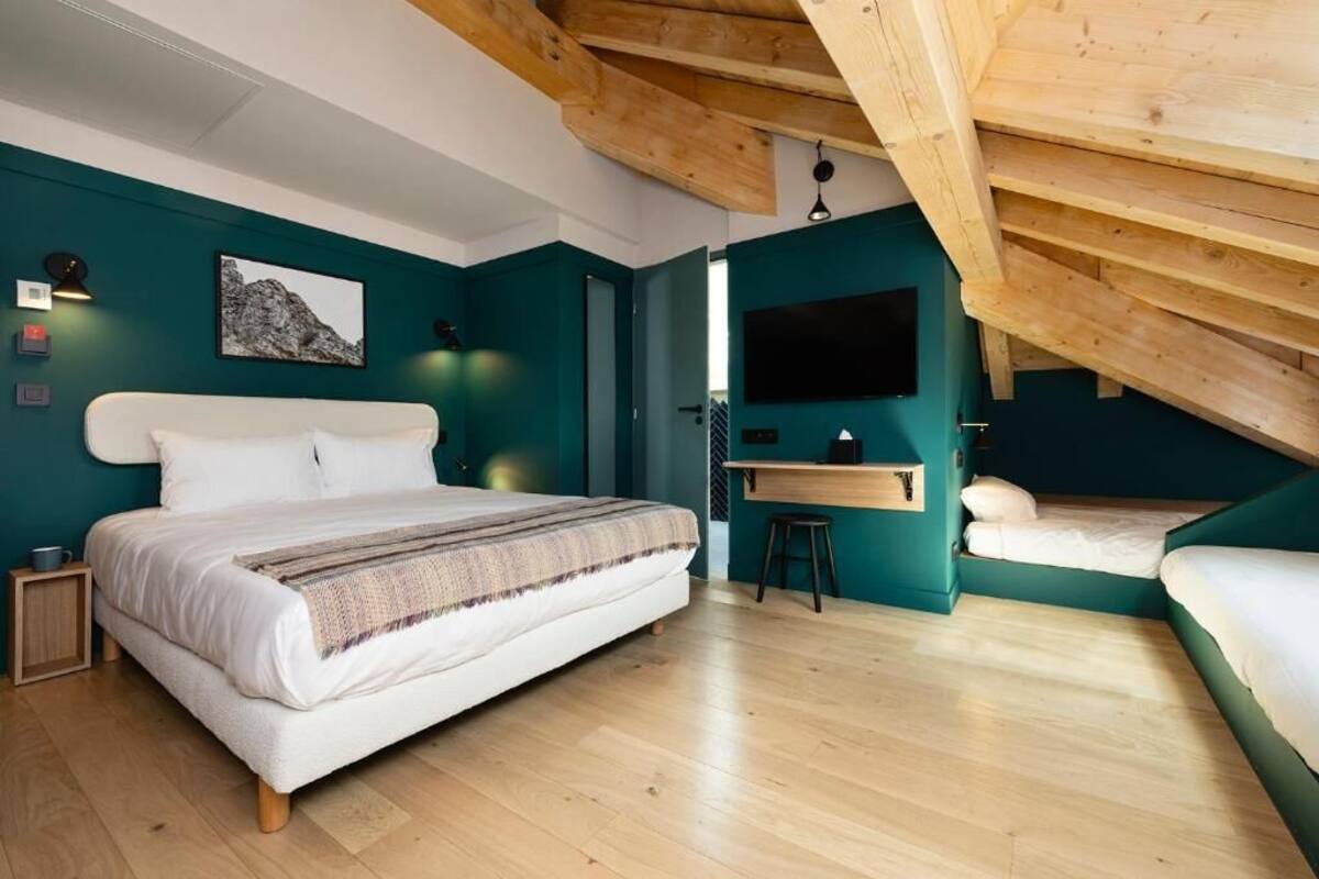 Une chambre avec un grand lit, un bureau et un petit tabouret.