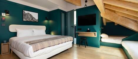 Een slaapkamer met een groot bed, een bureau en een klein krukje.