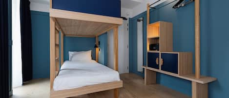 A bunk bed room with a wooden ceiling, a desk with a chair, and a wardrobe.