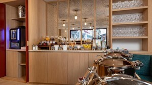 A breakfast bar with a coffee machine, jars of condiments, and a display of glassware.