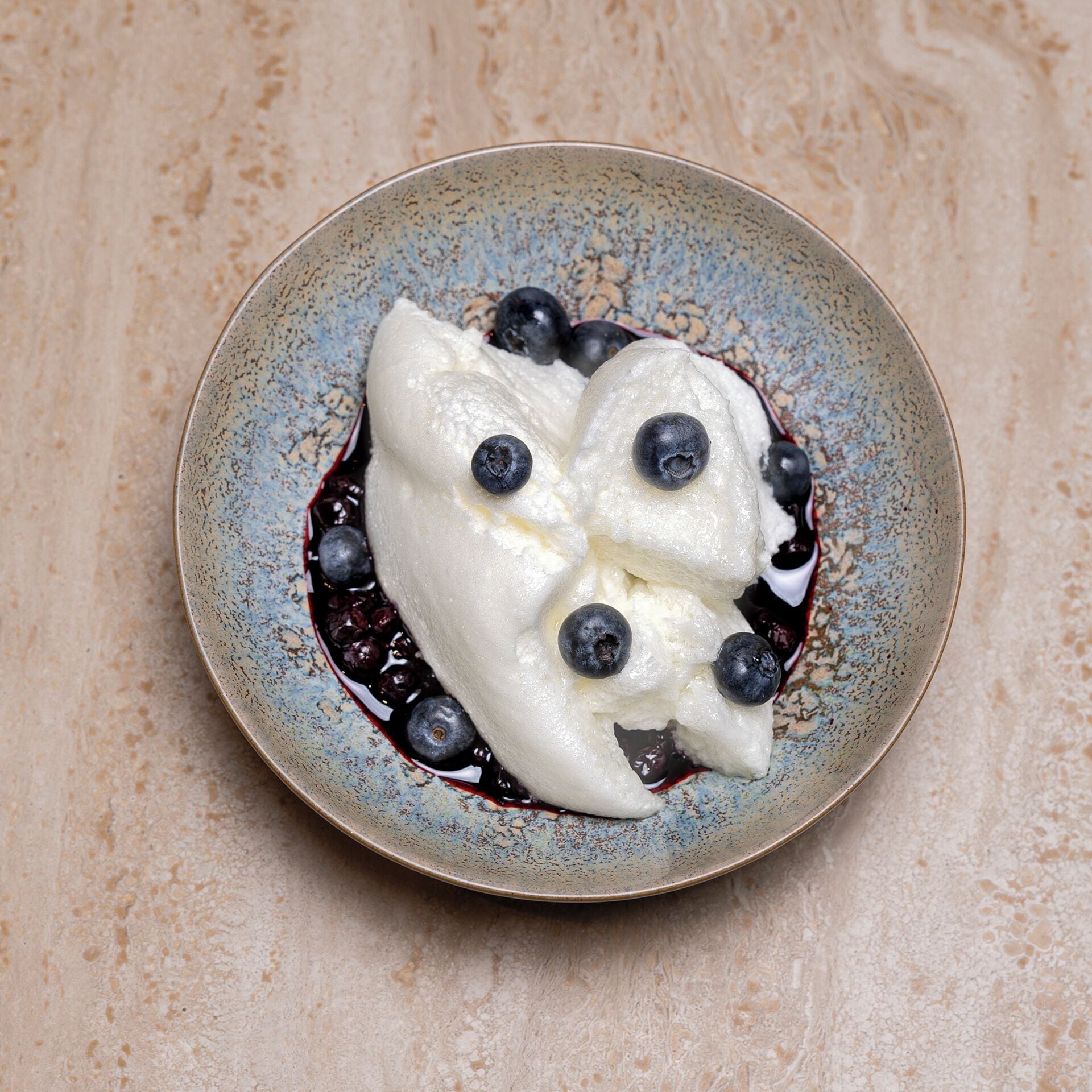 Un postre con arándanos sobre un plato de cerámica con textura.