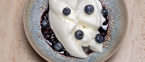 A dessert with blueberries on a speckled ceramic plate.